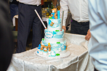 A three-tier blue and white birthday cake decorated with fondant, figurines in the shape of bears and a bunny with the male name Philip written in Cyrillic.