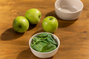 Fresh Green Apples and Spinach in White Bowls on a Wooden Table