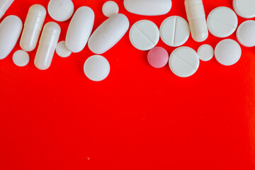 Various white and one pink tablet, presented in different shapes and sizes, are arranged vertically...