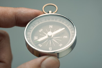 Close-up of a person’s hand holding a silver compass, symbolizing guidance, direction, decision...