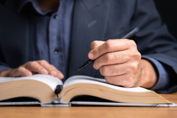 Close-up of businessman’s hands using pen to underline or highlight key information in an open...