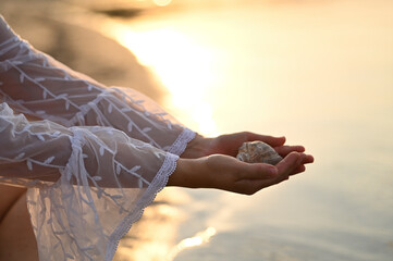 photo shoot of a woman in a white pareo and a black swimsuit at sunset on the beach