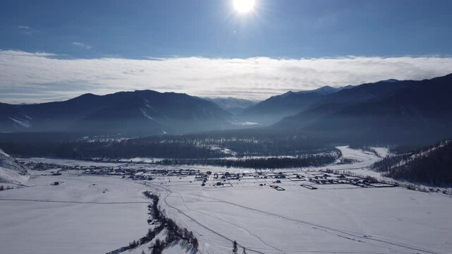 Drone footage of snowy mountains, valleys, and forests in Ust-Koksa, Altai Republic, Russia, under clear skies, showing the remote region&rsquo;s beauty during winter.