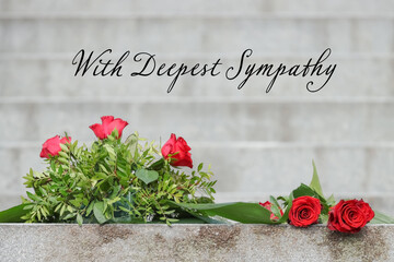 Condolence card with text: With Deepest Sympathy. Funeral floral arrangement of red roses. Memorial site at Hietaniemi cemetery in Helsinki, Finland. Beautiful funeral flowers on the stone steps. 