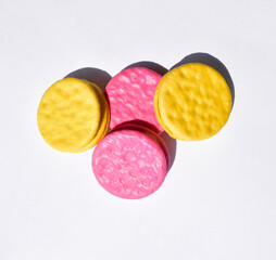 Pink and yellow round glazed biscuits isolated on white background, top view