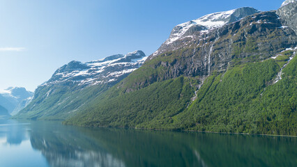 Fototapeta premium Steep mountain slope with waterfalls and snow above Lovatnet