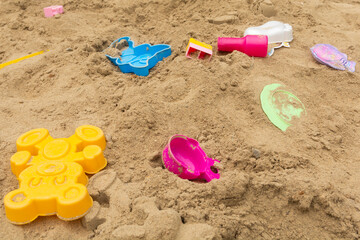 Abandoned children's toys on an outdoor sand playground