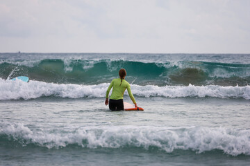 Sup surfing, girl going to ride on a board in a storm sea waves