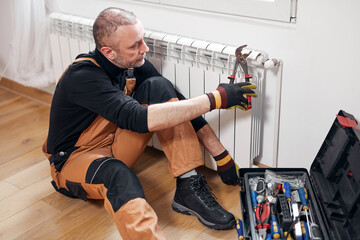 Central heating mechanic and handyman fixing home radiator, gas crisis and seasonal issues.
