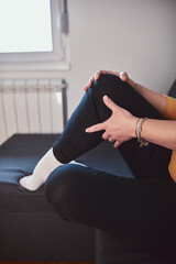 Woman with painful knee and leg injury at home.