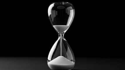 Hourglass with flowing white sand on black background depicting time, countdown, and deadlines.