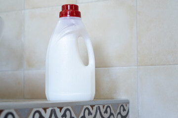 A clean bathroom countertop features a bottle of detergent. The decor combines stylish tiles and a fresh atmosphere.