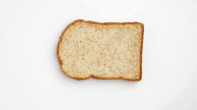 Rotating Top shot of sliced whole wheat bread, with golden crust, on white background