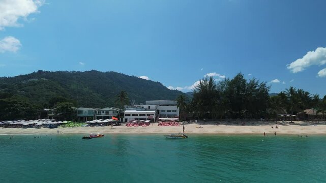 Cozy beach resort nestled in calm bay. Turquoise tropical sea gently washing loh dalum bay beach with white sand, beach umbrellas, restaurants and hotels in koh phi phi don, thailand, on sunny day