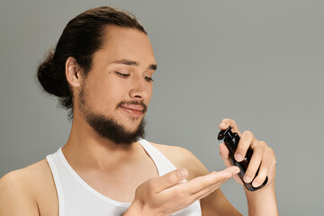 Handsome young bearded man applying grooming product in a casual indoor setting