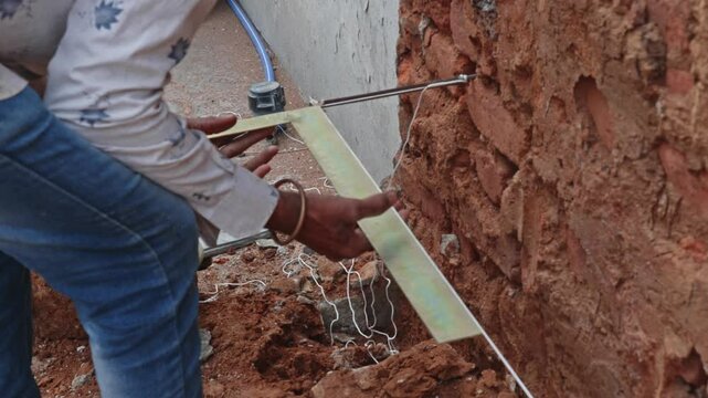 person aligning a string line using a 90-degree right angle scale on construction site. day time, zoom out shot, 4k.