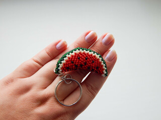 Red fruit keychain lies on a woman's palm