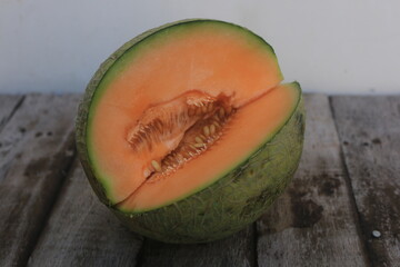 a melon that is cut open so that the orange flesh and many melon seeds are visible