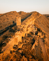 Aerial close up an ancient stone watchtower standing alone on a remote ridge. Georgia, symbolizing...