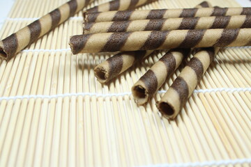 Chocolate wafer sticks with spiral pattern arranged on bamboo mat. Crispy sweet snack ideal for...