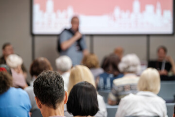 Unfocused view of an audience listening to a speaker during an educational event or presentation.