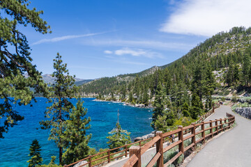 Walkway near Lake Tahoe, California, USA, offering great views of the clear blue lake and the snow covered mountains, early summer.