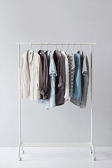 Collection of stylish clothes hanging on clothes hanger isolated on gray background with copy space, Closeup of clothing rack with jacket, shirt and t-shirt, Minimalist fashion blog.