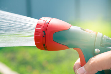The gardener waters the plants with a hose. A stream of water sprays from a garden hose.	