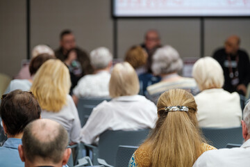 Audience at an event showing the back of seated attendees in an indoor venue.