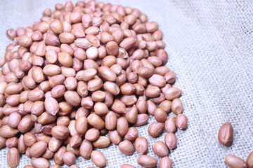 A heap of raw peanuts arranged on a burlap sack. Natural food background suitable for agriculture, farming, or organic product themes
