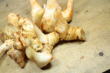 fresh galangal roots with distinct knobby texture arranged on a rustic wooden surface highlighting...