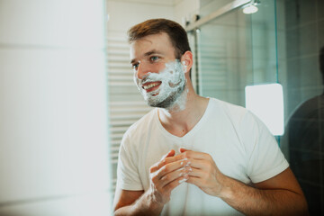 Young man shaving his beard