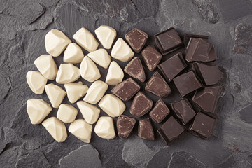 Elegant arrangement of dark, milk, and white chocolate squares on neutral textured surface with soft natural lighting