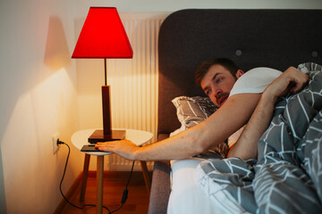 Man lying in the bed and scrolling before sleep