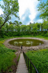 Fototapeta premium Scenic meteorite crater lake Kaali surrounded by forested terrain.
