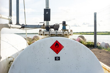 Industrial fuel storage tank with warning labels and piping system.