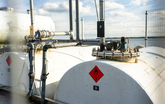 Industrial fuel storage tank with warning labels and piping system.