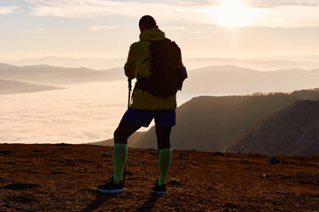 Solitary Hiker Resting at the Mountain Summit During a Golden Sunset.