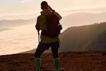 Solitary Hiker Resting at the Mountain Summit During a Golden Sunset.
