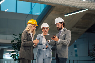 Architects using tablet discussing blueprint in modern office building