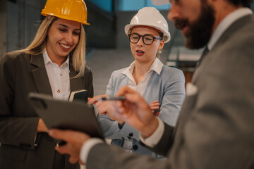 Engineers and businessman discussing project on tablet in industrial building