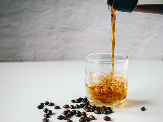 Pouring black coffee into glass with ice. ice coffee drink pour americano and coffee beans ....