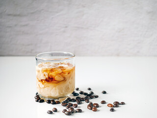 Ice coffee in glass with milk poured mix and beans on a white table, Latte coffee ice