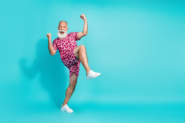 Full size photo of funny aged man raise fists empty space wear leopard print outfit isolated on...