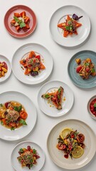 Overhead shot of an assortment of colorful tomato salads on plates against a white background
