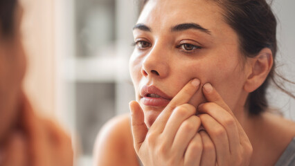 Woman squeezing a pimple or blackhead on her face