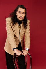 Charming young man with a beard displaying confidence against a vibrant red backdrop