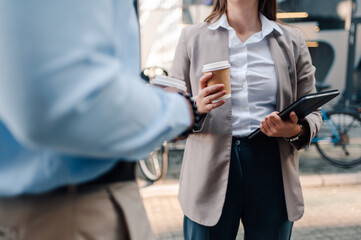 Business people holding takeaway coffee and tablet during informal meeting