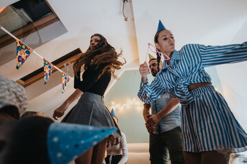 Group of people celebrating a birthday in a cozy home setting, with decorations and party hats,...