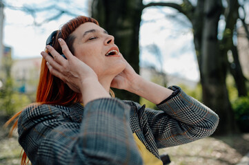 Businesswoman listening music with headphones in a park